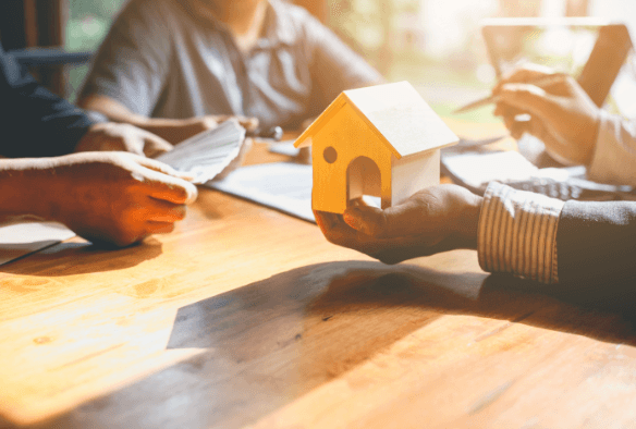 A seller selling a mini house with the buyer counting money for payment. 